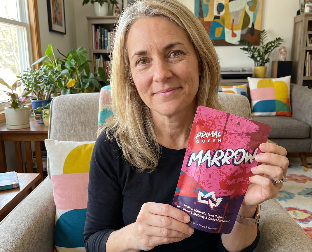 Shelby, the founder of Primal Queen, sitting in her living room holding a pouch of Marrow