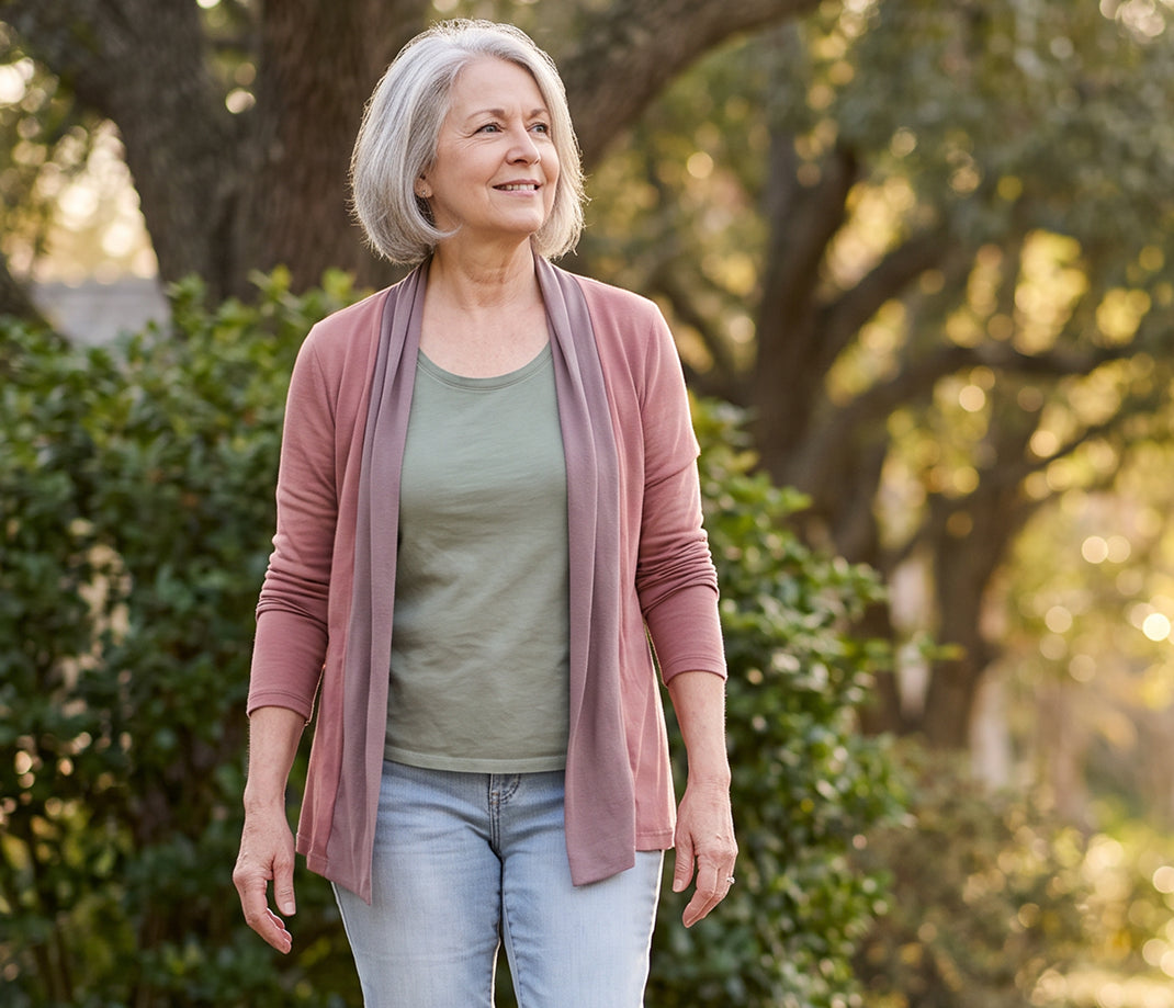 A woman walking along a tree-lined path, smiling